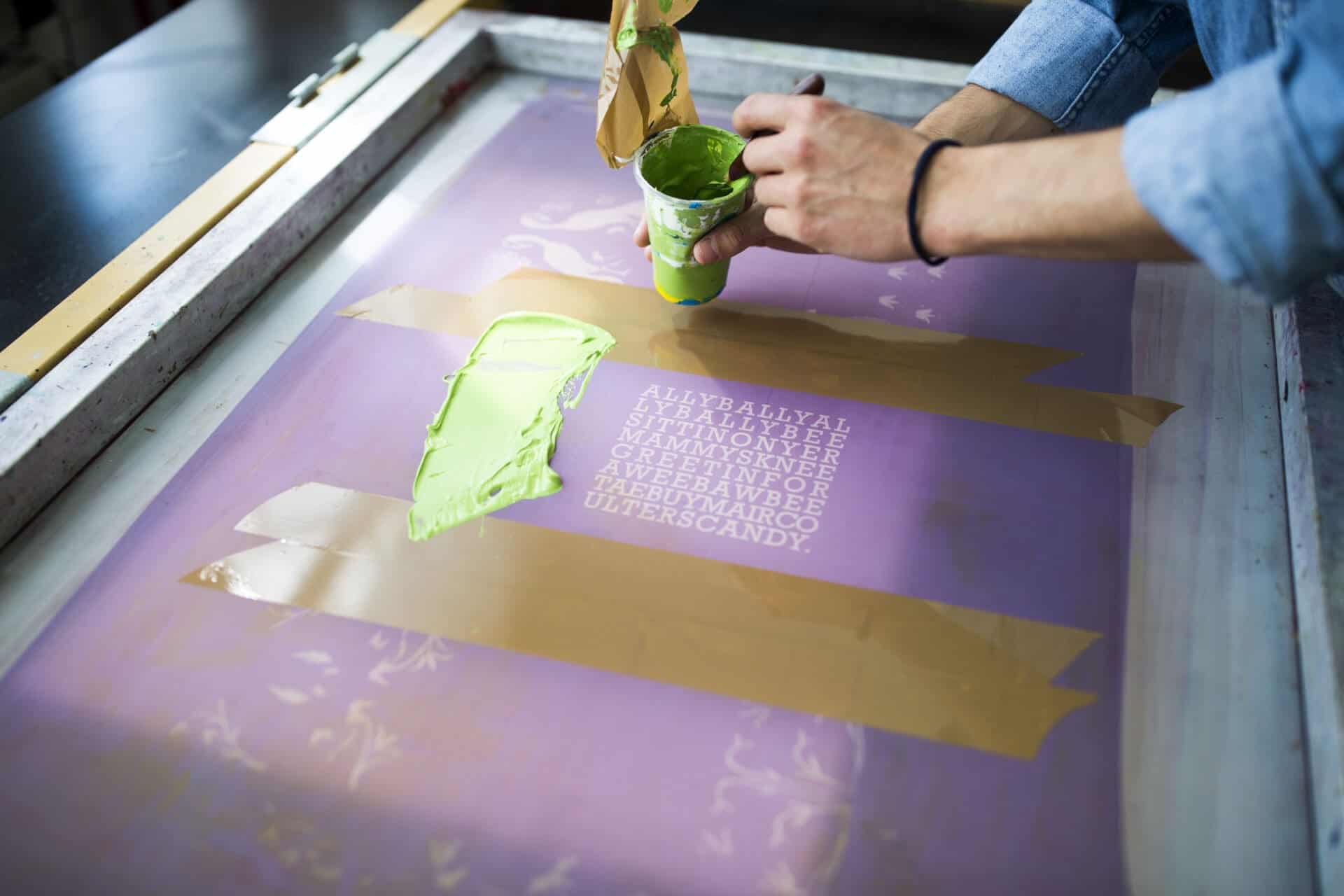 Hands Of Male Printer Applying Green Ink To Silkscreen In Printing Press Studio